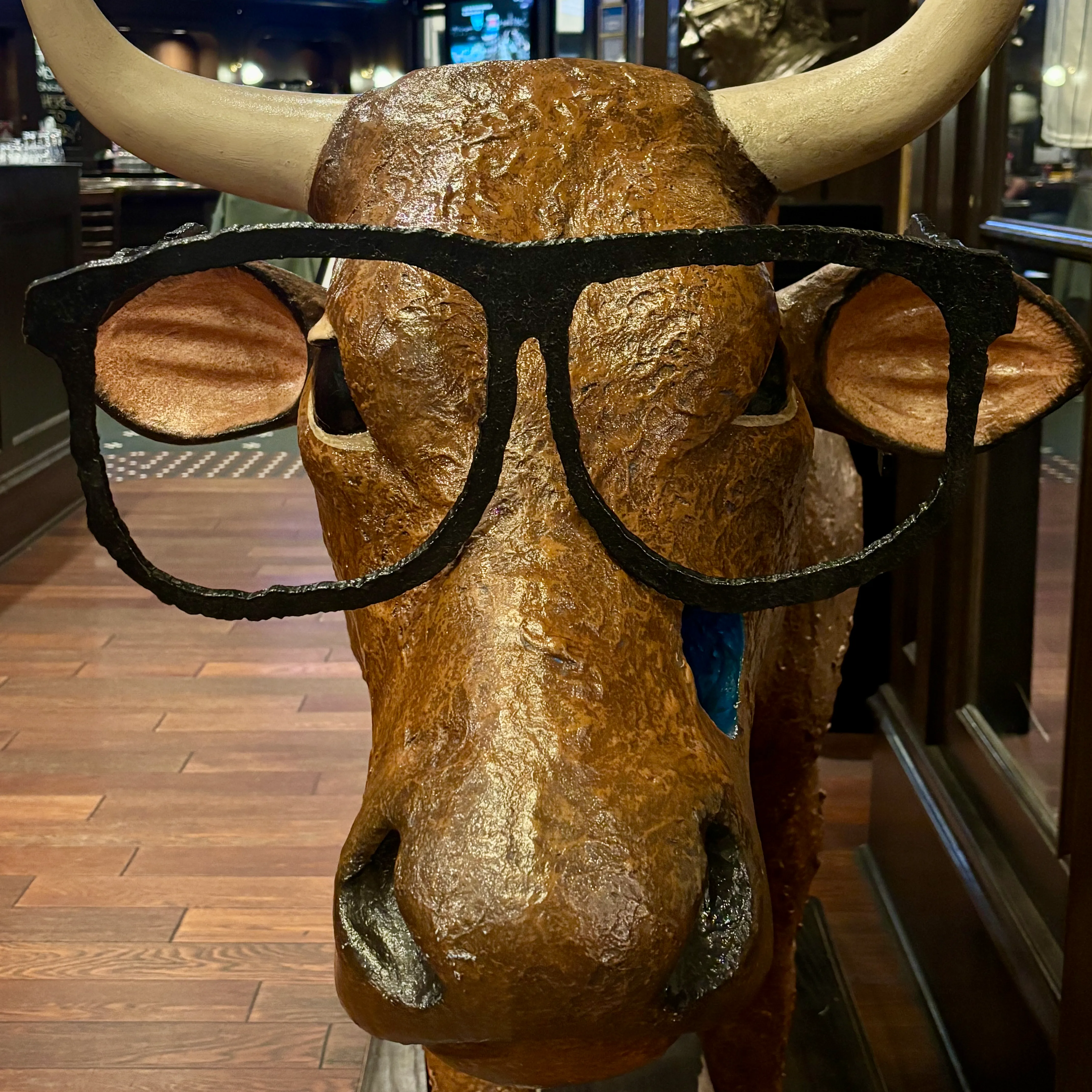 A brown cow head sculpture wearing oversized black glasses