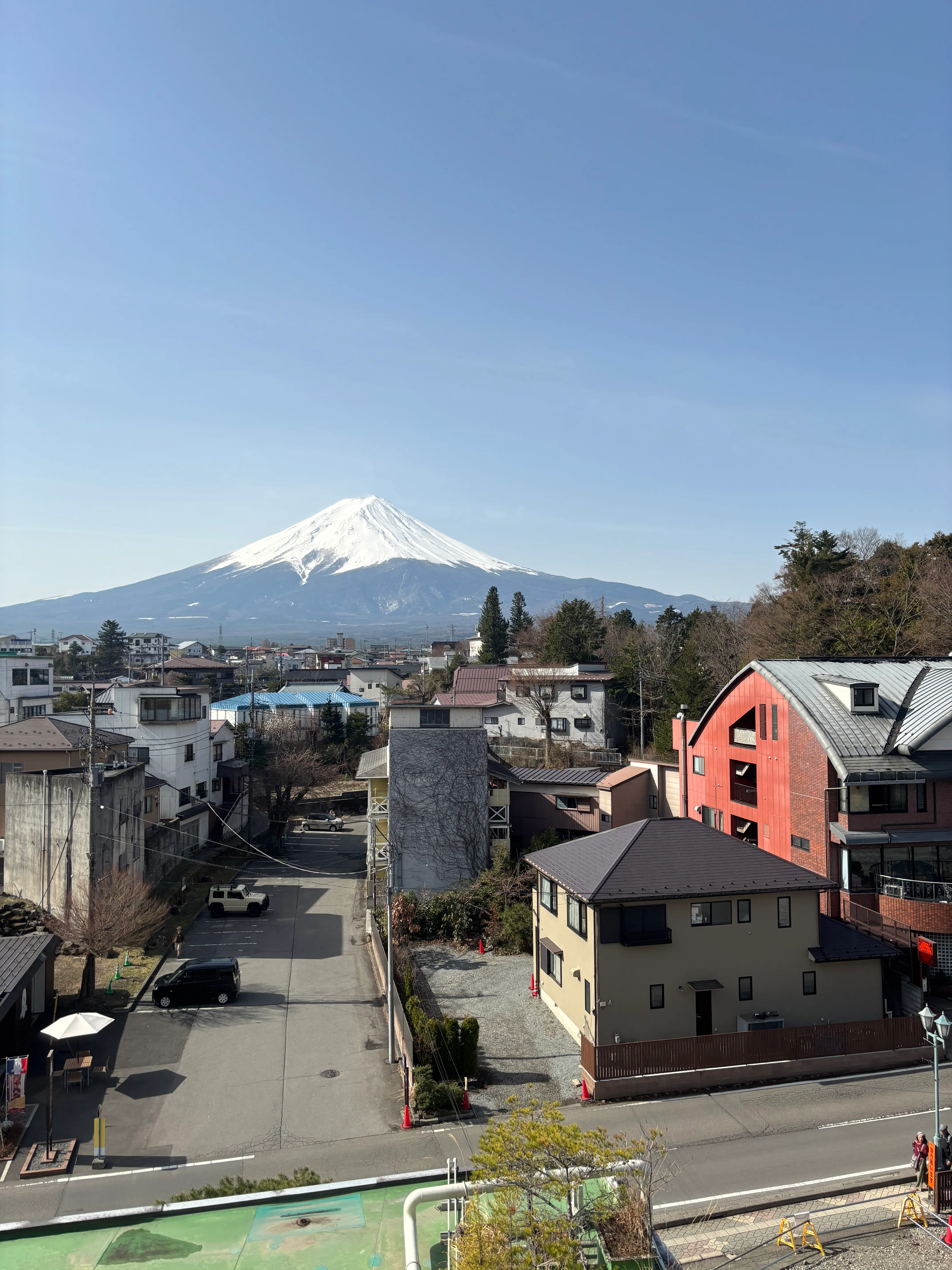 Cross streets with colorful buildings and trees, with Mt. Fuji in the distance