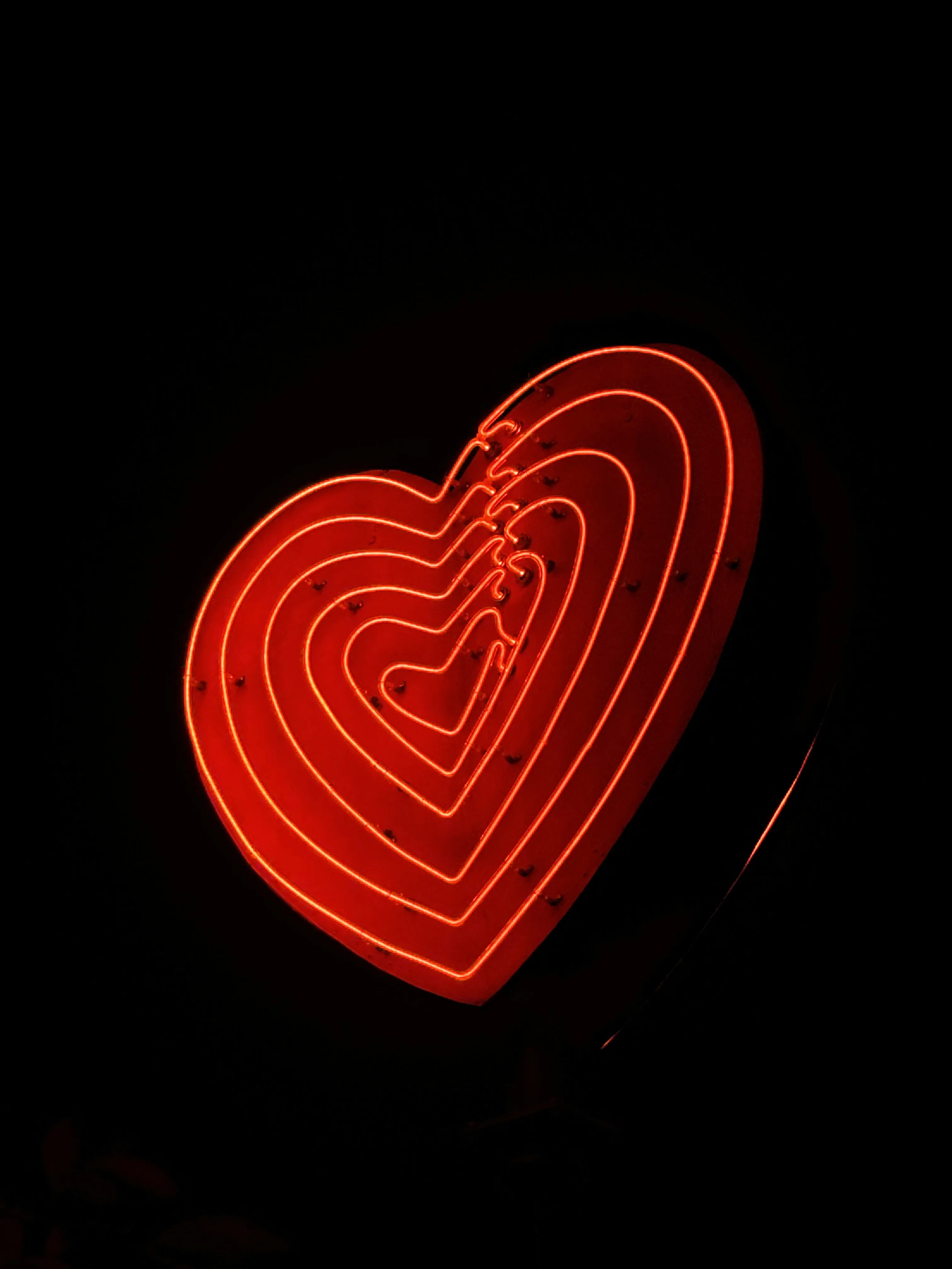 A neon heart sign, consisting of six layers of hearts, increasing in size from the center