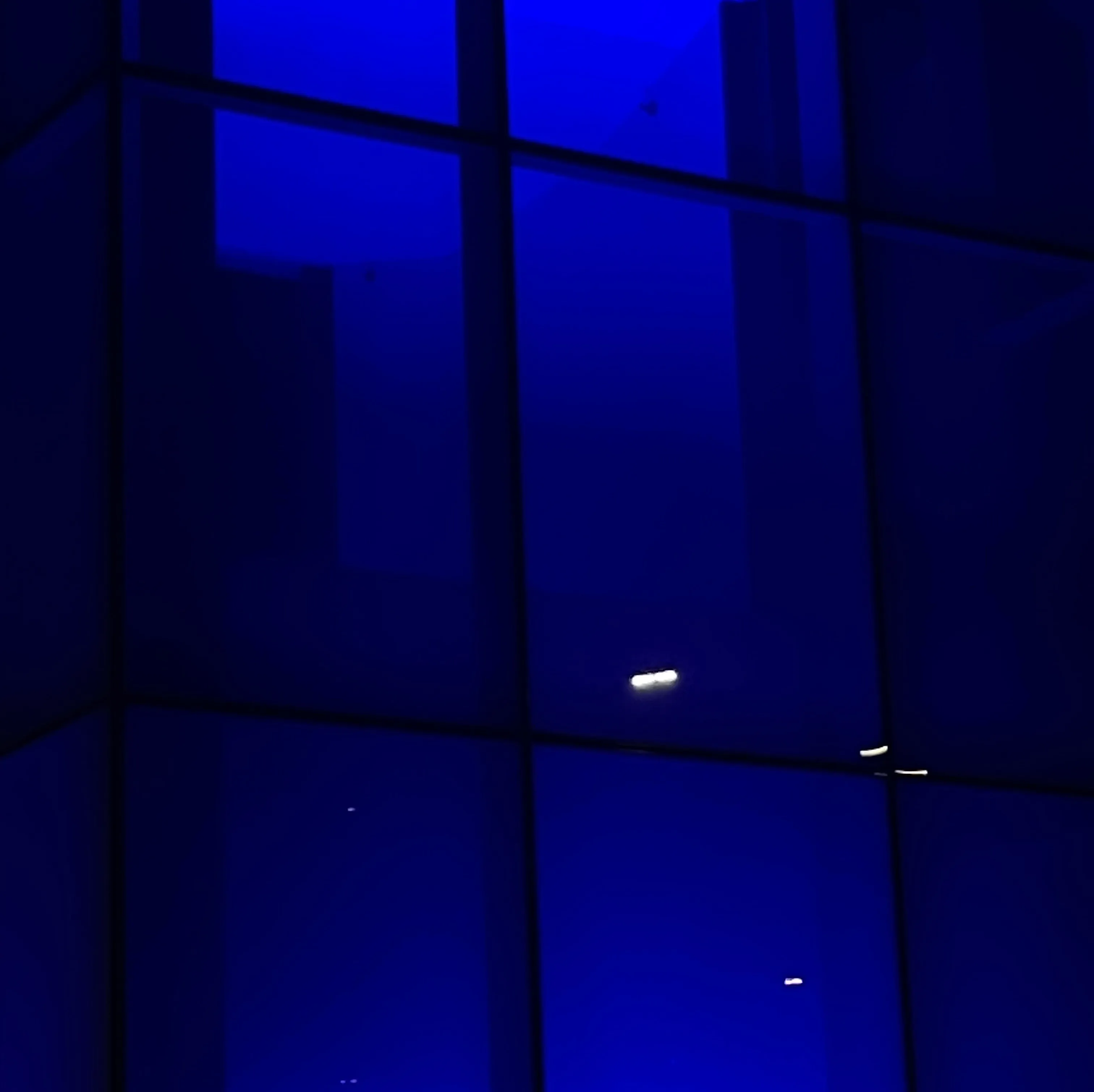Window with a grid-like pattern illuminated by dark blue light