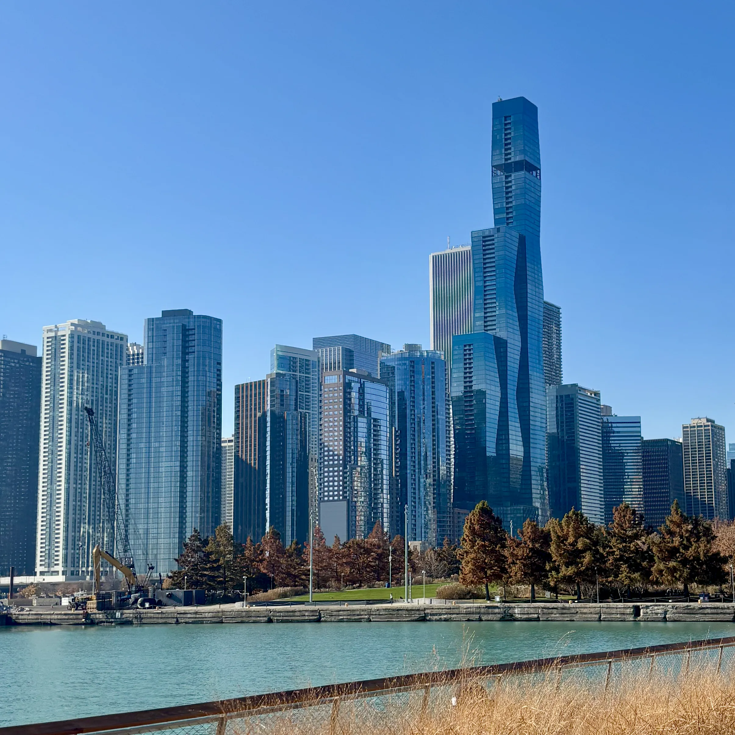 Chicago skyline viewed from Navy Pier featuring St. Regis Chicago tower and autumn trees under a clear blue sky